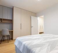 A bright bedroom with a desk, wardrobe, and bed in a 2-room apartment.