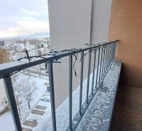 A balcony with Christmas lights, a snow cover, and a view of Poprad and family houses.