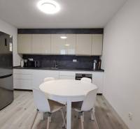 A kitchen in a family house with a refrigerator, a round table, and a floor with a wooden decor.