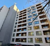 High-rise residential building in Poprad with a parking lot and trees in the surroundings.