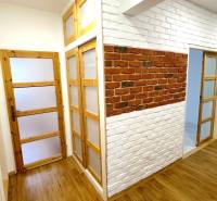 Interior of a 3-room apartment with a wooden decor floor and brick cladding.