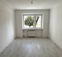A room with a large window, a floor with a wooden decor, a 3-room apartment.