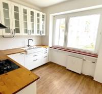 A kitchen in a 3-room apartment with white cabinets and a wood-patterned floor.