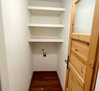 A small room with a wooden decor floor and shelves in a 3-room apartment.