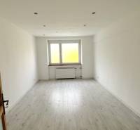 An empty room in a 3-room apartment with a window and a floor with a wooden decor.