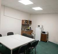 Dining room in offices with a white table, chairs, and kitchen equipment.