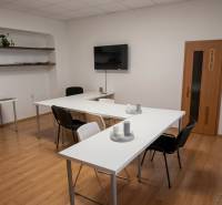 Offices with white desks, black chairs, and wood-patterned flooring.
