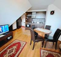 Kitchen with dining table and TV, 3-room apartment with wood-patterned flooring.