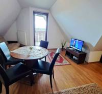 A living room in a three-room apartment with a wooden decor floor and a dining table.
