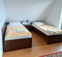 A bedroom with two single beds, a nightstand, and a wooden-patterned floor in a three-room apartment.