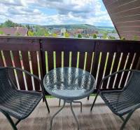 A balcony with rattan chairs and a round table offers a view of Veľká Lomnica.