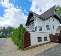 A family house surrounded by green thuja trees on the street of Veľká Lomnica.