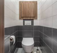 A bathroom with white and gray tiles, wooden decor cabinet, 4-room apartment.