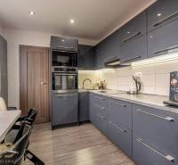 A kitchen in a 4-room apartment with a wood-patterned floor and modern furniture.