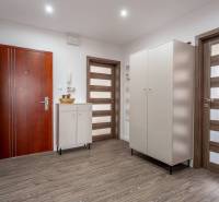Entrance hallway with a wardrobe and a cabinet, floor with wooden decor in a 4-room apartment.