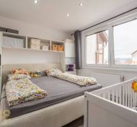 Bedroom in a 4-room apartment with a bed, storage space, and a baby crib.