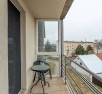 The balcony of a 4-room apartment with a view of Poprad includes a table and a chair.