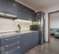 A kitchen in a 4-room apartment with a dark kitchen unit and a floor with a wooden decor.
