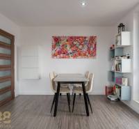 Dining area with a table and paintings in a 4-room apartment with wood-patterned flooring.