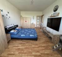 A bedroom in a 3-room apartment with a wood-patterned floor and furniture.