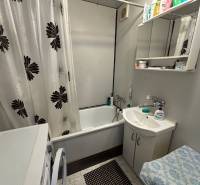 Bathroom with a shower curtain, white furniture, and flooring in a 3-room apartment.