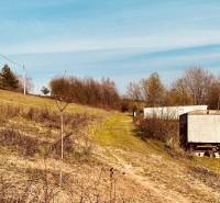 A sloped plot of land with grass cover and a solitary cart in Nová Kelča, recreational plots.