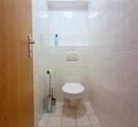 A toilet with white tiles in a 2-room apartment.