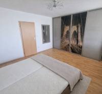 Bedroom in a 2-room apartment with a double bed, wardrobe, and floor with wood decor.