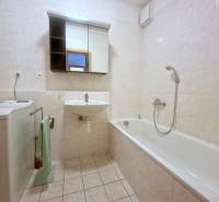 Bathroom in a 2-room apartment with a bathtub, washing machine, and mirrored cabinet.