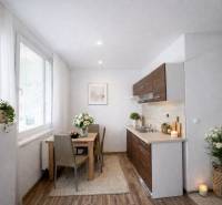 A kitchen in a one-room apartment with a wooden decor floor and flowers on the table.