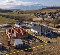 A family house in Tvarožná with construction work in the background of a mountain massif.