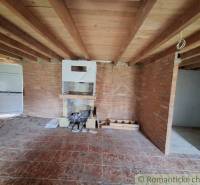 Brick walls, wood-patterned floor, ceiling beams, and a fireplace in the cabin.