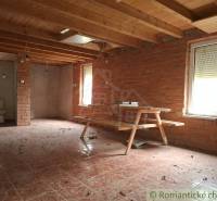 A cottage with brick walls, a wooden decor floor, and simple furniture.
