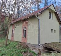 A cottage in Chľaba surrounded by trees and nature on a sloping plot.