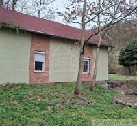 A cottage in the village of Chľaba with brick details and a red roof, surrounded by nature.