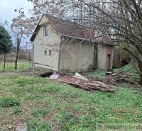 A cottage in Chľaba surrounded by trees and greenery awaits renovation.