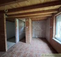 Interior of a cabin with brick walls, a wooden decor floor, and exposed electrical wiring.