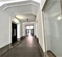 A hallway with vaulted ceilings, white walls, and doors in the background.