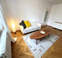 Living room with wood-patterned flooring, sofa, and table in a two-room apartment.