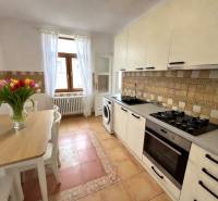 A kitchen in a 2-room apartment with flowers on the table and ceramic tiles.