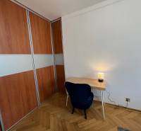 A room with a desk, chair, wood-patterned floor, and built-in wardrobe.