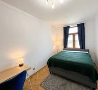 Bedroom in a 2-room apartment with a bed, table, and lamp, floor with wooden decor.
