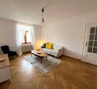 Living room in a 2-room apartment with a wooden decor floor, sofa, and table.