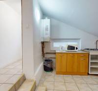 A kitchen in a 3-room apartment with a tiled floor, kitchen unit, and microwave.