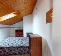 Attic room with a bed, wooden ceiling decor, radiator, and small mirrors.