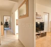 A hallway in a 3-room apartment with a wooden decor floor and furniture.