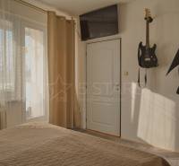 Guitars on the wall in the bedroom of a three-room apartment with a TV on the wall.