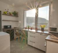 A kitchen with a window, kitchen unit, plants, and a microwave in a 3-room apartment.