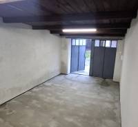 The interior of a garage with white walls and a metal door.