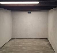 An empty garage with a concrete floor and a wooden ceiling, bright plastered walls.